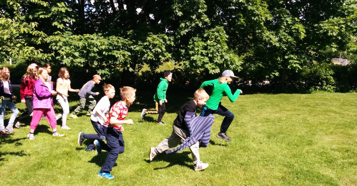 Lapset juoksevat ulkona kesän tiedeleirillä.