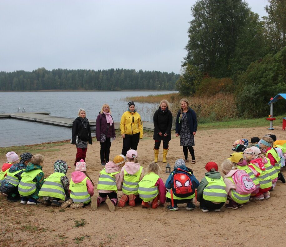 Oppilaita rannalla yhdessä opettajien kanssa.