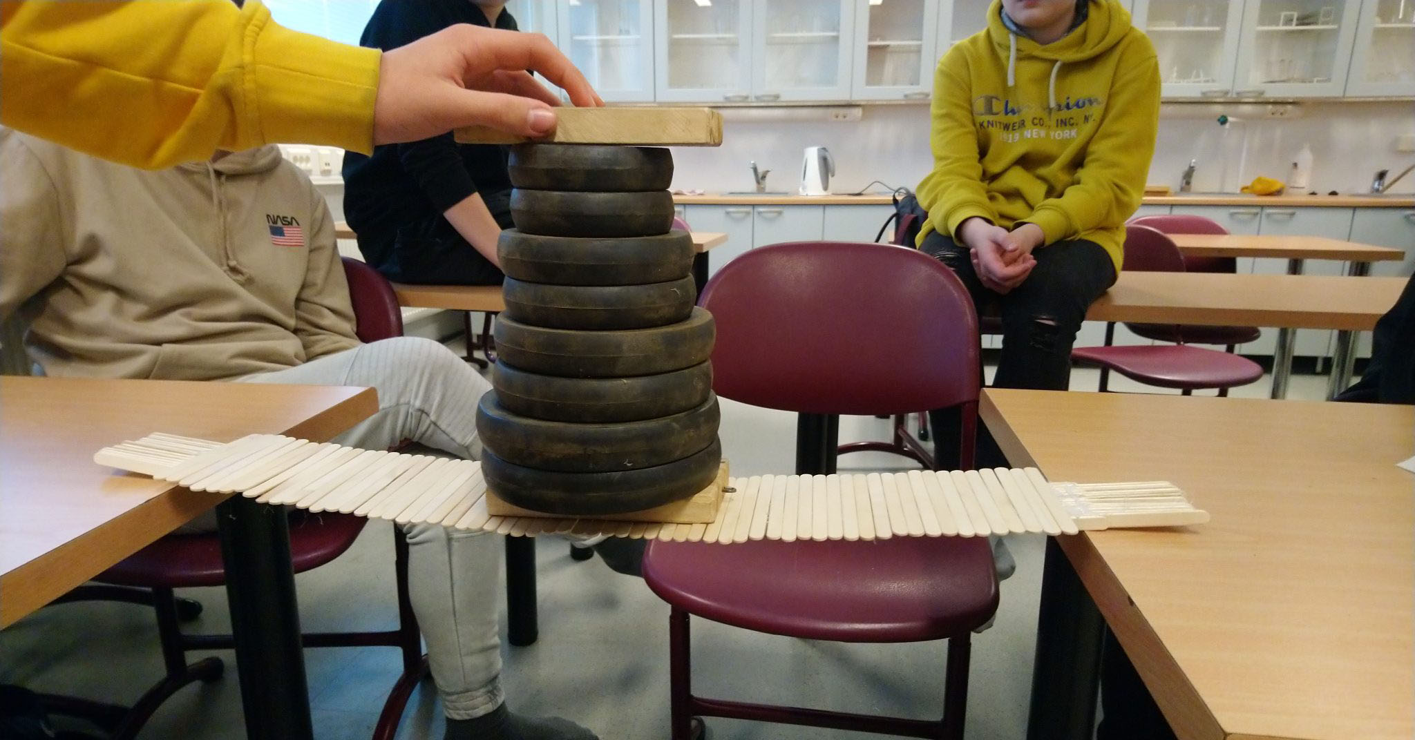 Nuoret rakentavat tornia mustia painoja käyttäen.