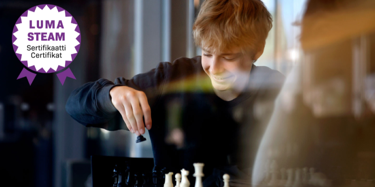 Valokuvassa teini-ikäinen poika pelaa shakkia. Kuvan päällä on LUMA/STEAM-sertifikaatin logo.